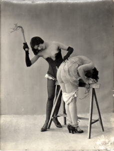 Uma dominadora castigando uma submissa. Foto produzida pelos irmãos Biederer na década de 1930.